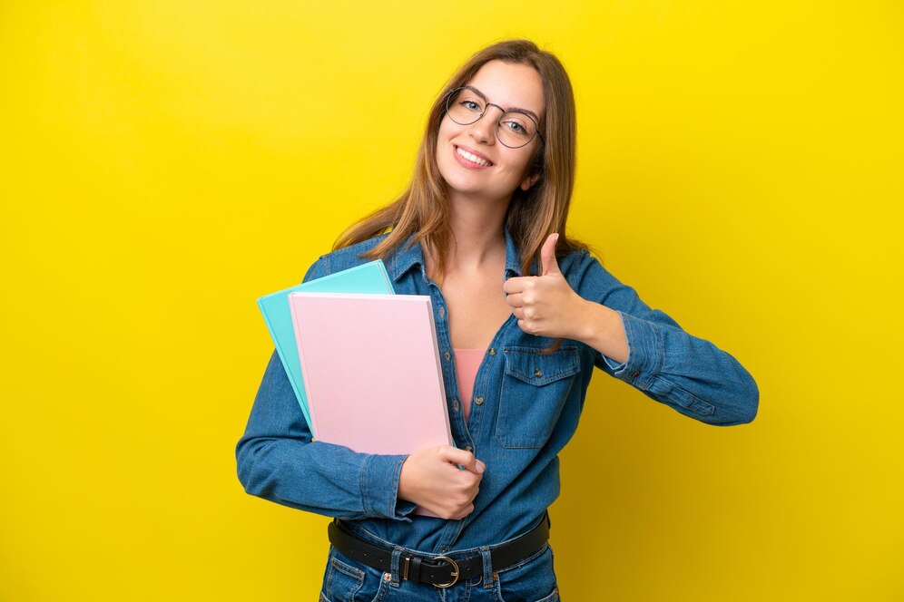 young student caucasian woman isolated yellow background giving thumbs up gesture 1368 346842